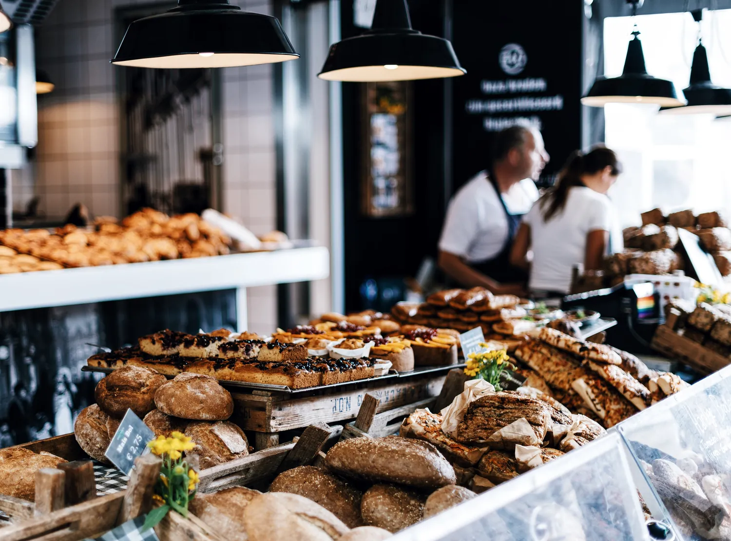 Staff behind a bakery counter full of loaves and pastry