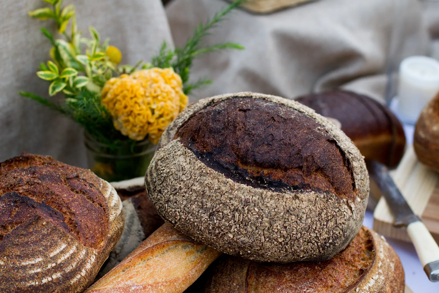 Dark crusted loaves with yellow flowers on a table