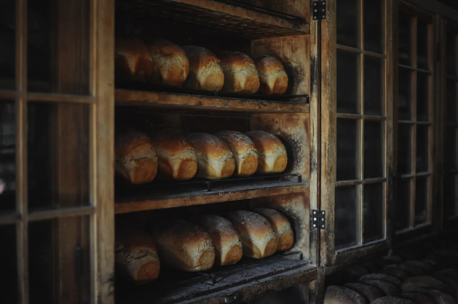 Loaves cooling on racks in a wooden oven cabinet