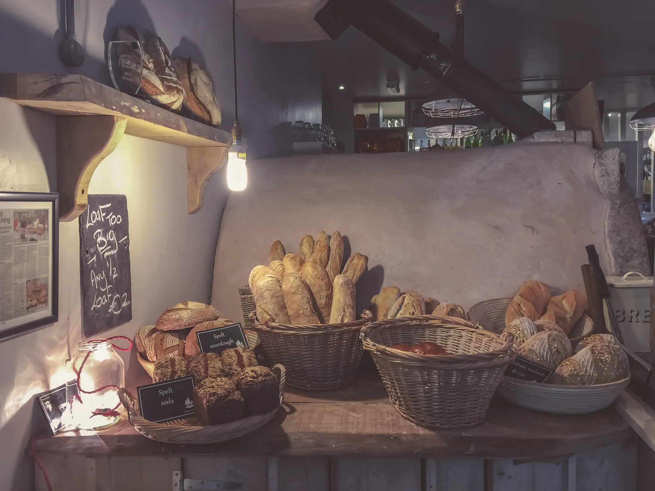 Rustic loaves of bread in baskets on a dark wooden shelf
