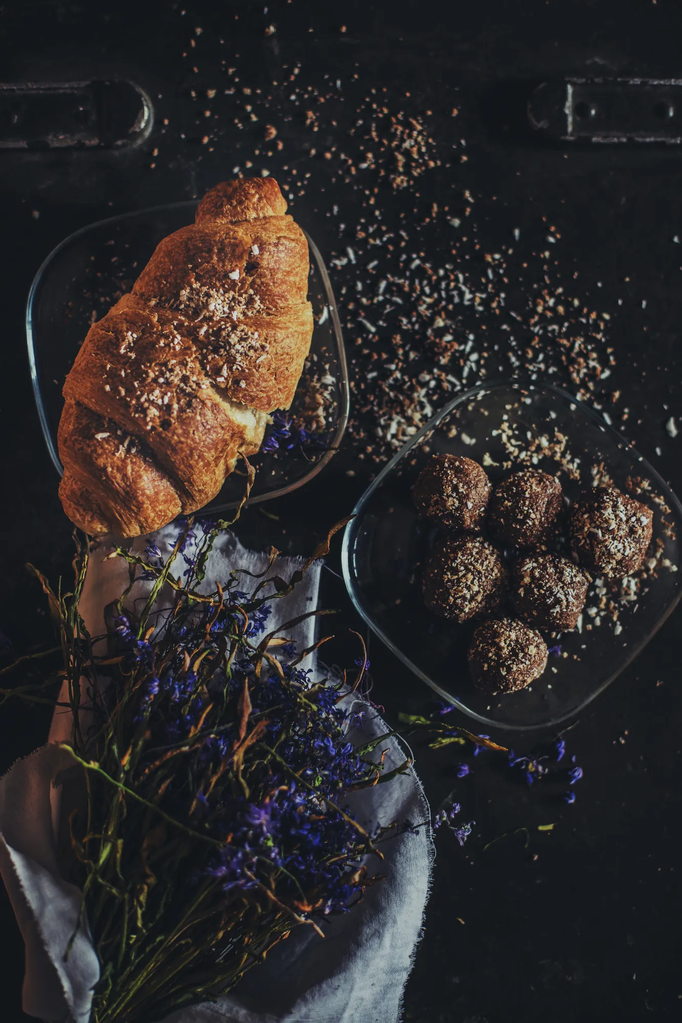 A croissant and small cakes on a dark surface