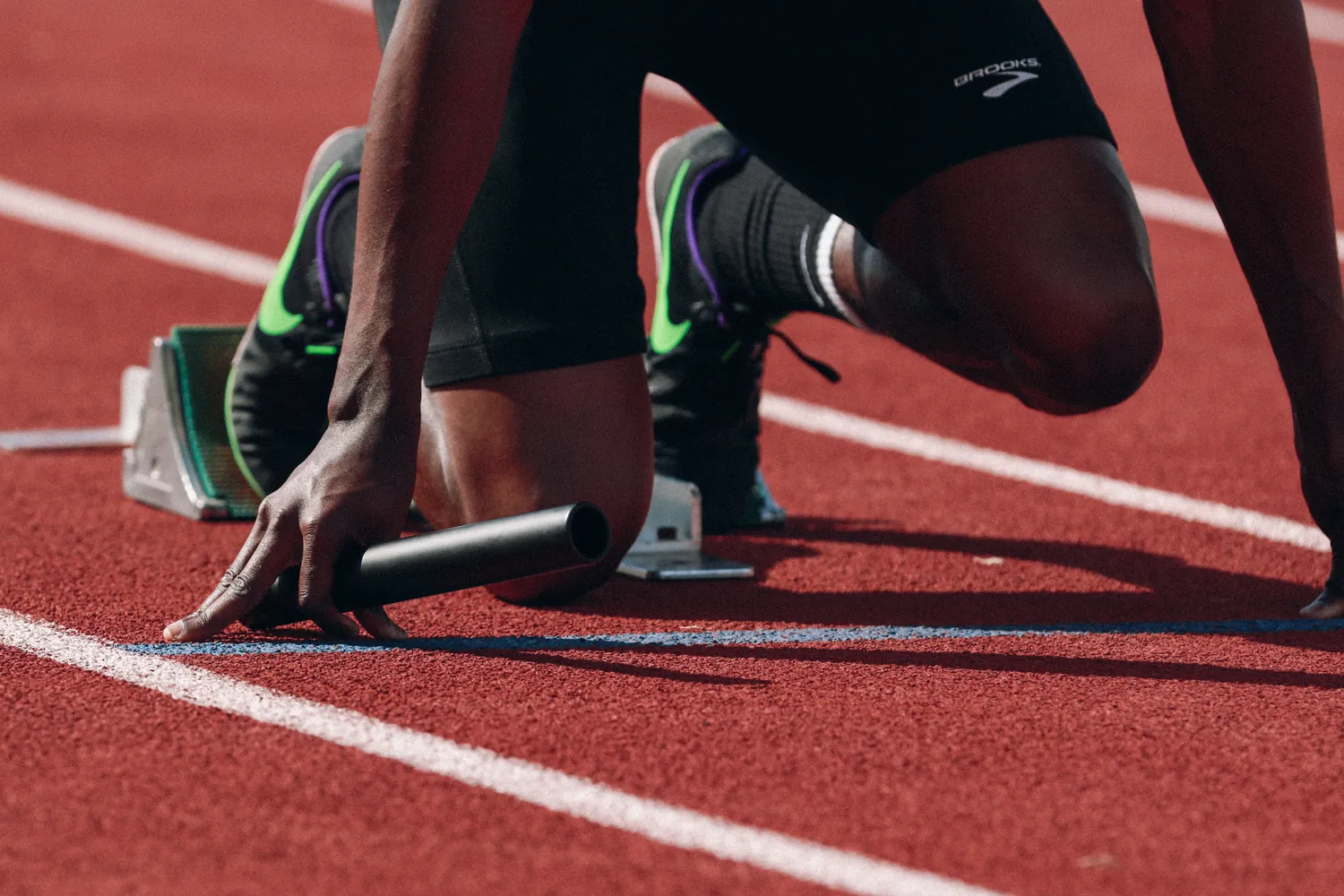 A sprinter in the starting blocks on a red track