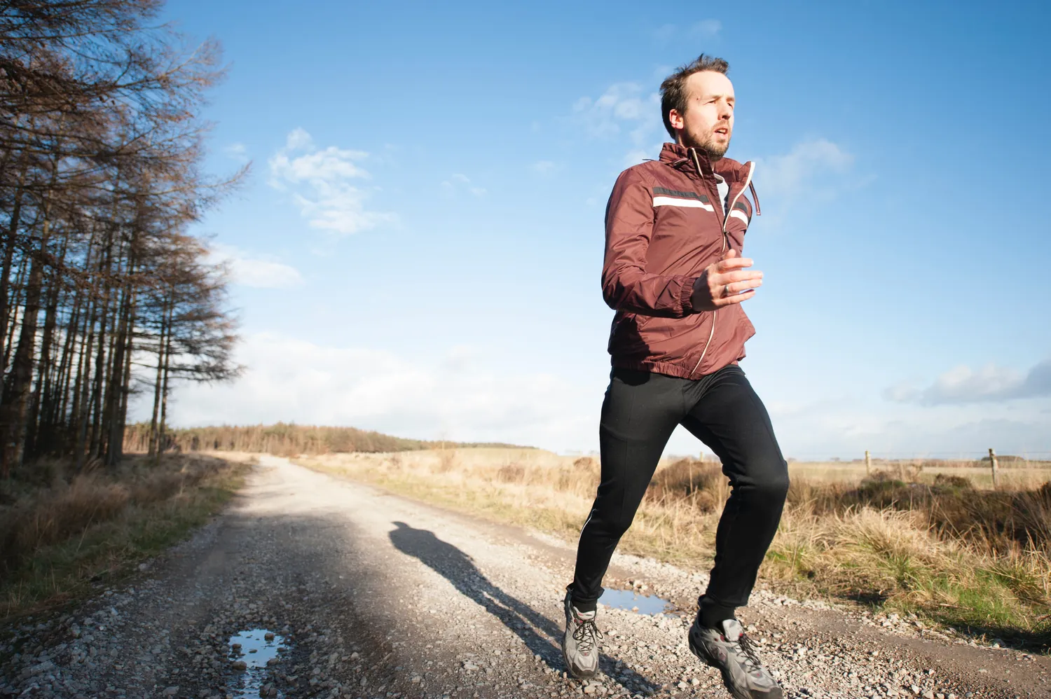 A man in a red jacket running on a rural path