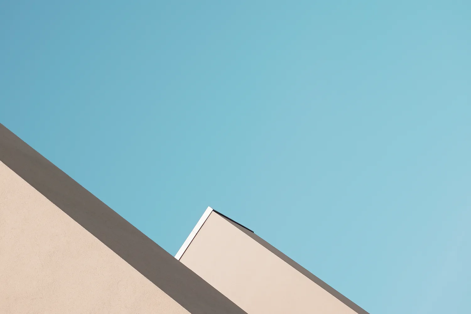 Two pale roof edges against a pale blue sky