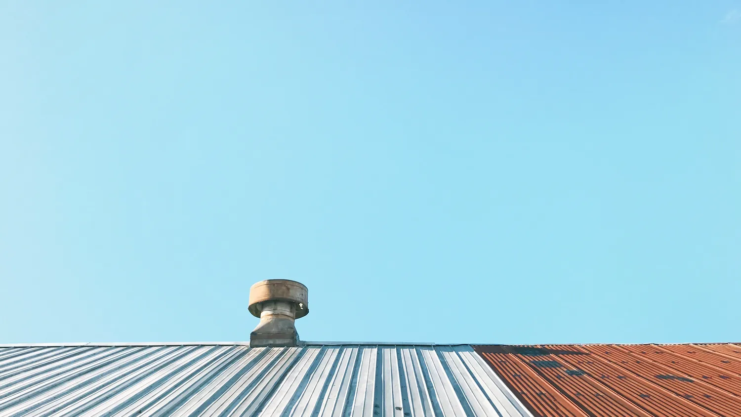 A corrugated metal roof line against a clear blue sky